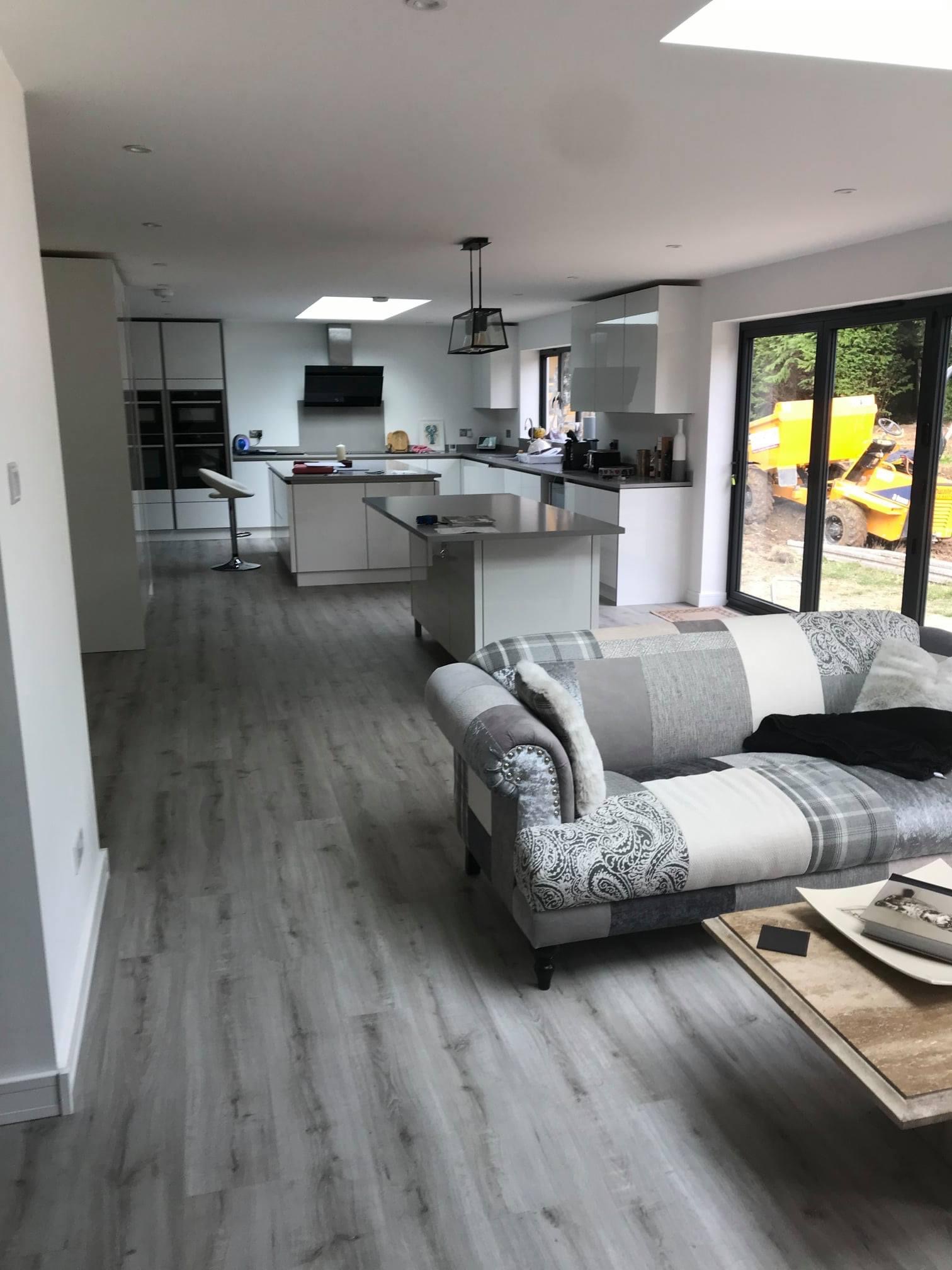 Finished open-plan kitchen and living extension with grey wood-effect flooring