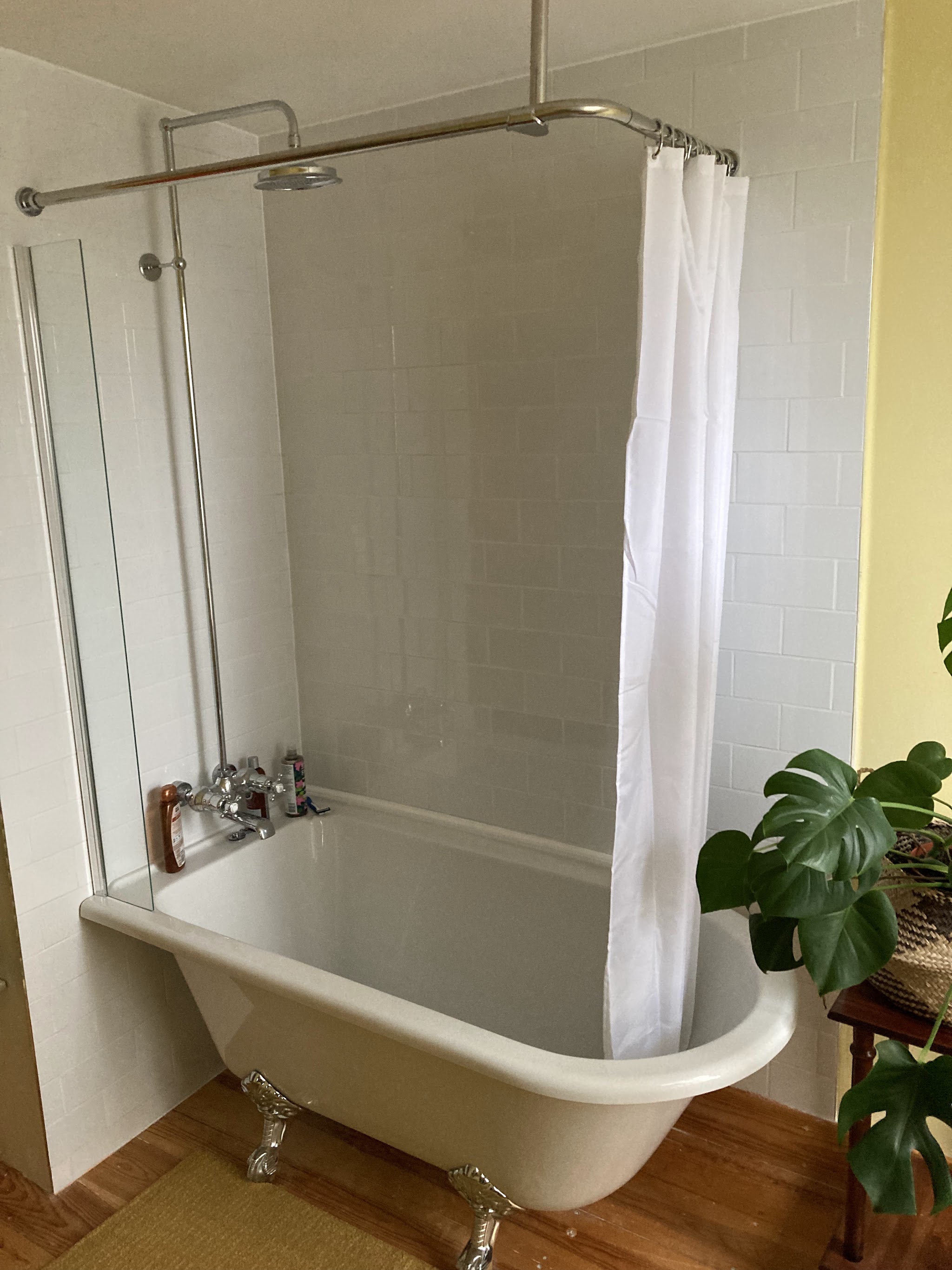 Freestanding roll-top bath with a shower curtain rail and white metro tiles