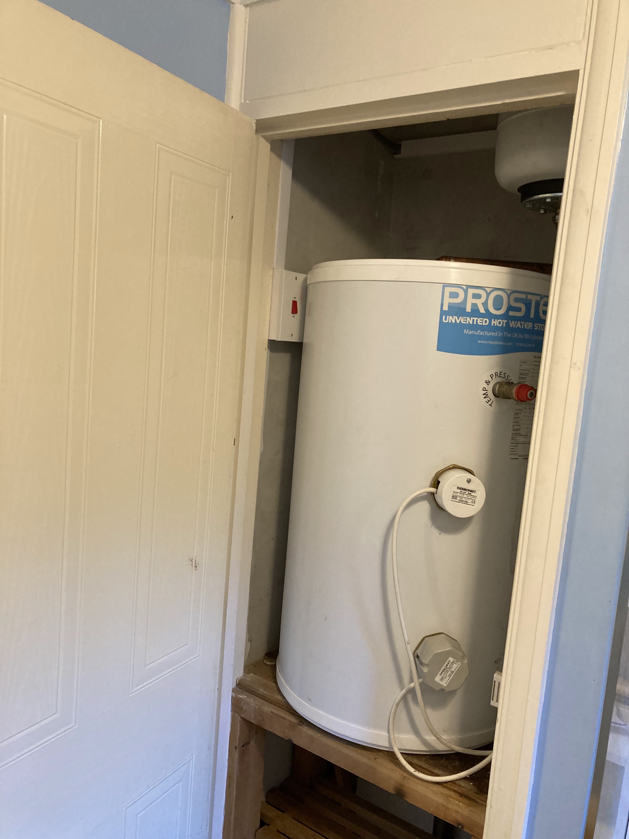 White unvented hot water cylinder fitted in an airing cupboard